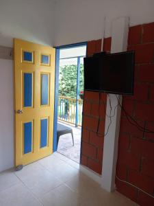 a room with a door and a tv and a brick wall at LA RIVERA HOSTERIA CAMPESTRE in Villamaría