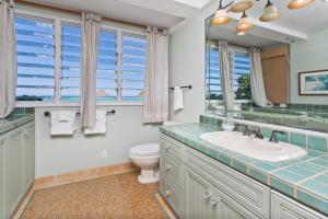 a bathroom with a sink and a toilet and windows at Hale Kainalu in Kailua