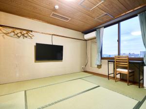 um quarto com uma televisão, uma secretária e uma cadeira em Okasan Hotel - Vacation STAY 77675v em Ogaki