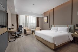 a hotel room with a large white bed and a desk at Wanda Yue Suzhou Huangdai in Suzhou
