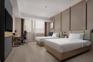 a hotel room with two beds and a flat screen tv at Wanda Yue Suzhou Huangdai in Suzhou
