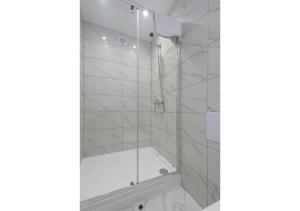 Un baño con ducha con azulejos blancos. en Splendid and Comfy 1 bedroom apartment, en Londres