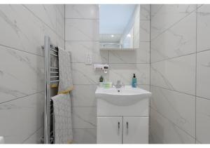 Un baño blanco con lavabo y espejo. en Splendid and Comfy 1 bedroom apartment, en Londres