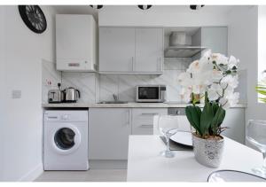 une cuisine blanche avec un lave-linge et un vase de fleurs dans l'établissement Splendid and Comfy 1 bedroom apartment, à Londres