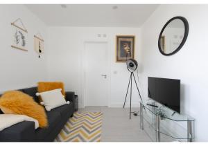 - un salon avec un canapé noir et un miroir dans l'établissement Splendid and Comfy 1 bedroom apartment, à Londres