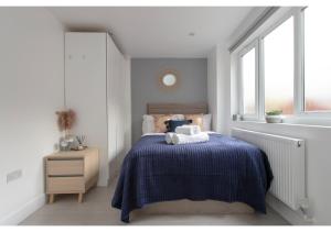 a bedroom with a bed with a blue blanket and a window at Splendid and Comfy 1 bedroom apartment in London