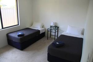 a bedroom with two beds and a ottoman and a window at Southern River Family Accommodation. Free WiFi in Perth