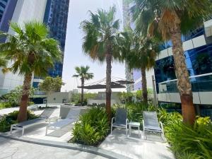 a patio with chairs and palm trees in front of a building at AMAZNING VIEW & PARAMOUNT BRANDED TWO BEDROOM APARTMENTS BRUJ VIEW in Dubai