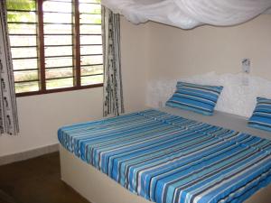 a bedroom with a bed with blue and white stripes at Safina Cottages in Diani Beach