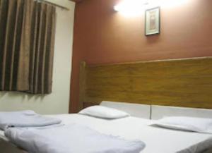 a bedroom with two beds with white sheets and a wooden headboard at Hotel Ajay International Agra in Agra