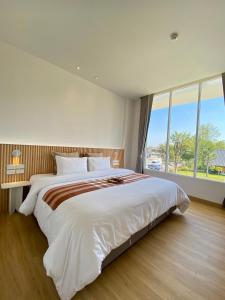 um quarto com uma cama grande e uma janela grande em Punn Hotel Korat em Nakhon Ratchasima