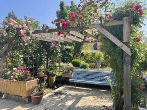 eine hölzerne Pergola mit einer blauen Bank und Blumen in der Unterkunft La Maison d'Andrée in Pluvet