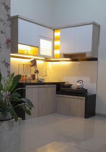 eine Küche mit weißen Schränken und einem Herd in der Unterkunft VILLA YANTI PERMATA GARDEN in Karangploso + 2 Fotos