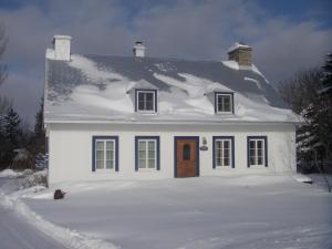 a white house with snow on top of it at Au Vieux Foyer in St-Pierre-de-l'Île-d'Orléans