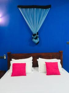 een blauwe slaapkamer met een bed met 2 rode kussens bij Yala Grand Homestay in Tissamaharama
