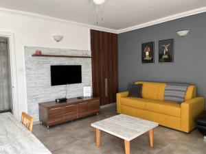 - un salon avec un canapé jaune et une télévision dans l'établissement Apartment in Swieqi with communal pool, à Tal-Għoqod