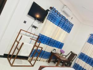 een kamer met blauwe gordijnen en een tv bij Yala Grand Homestay in Tissamaharama