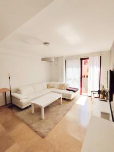 a white living room with a white couch and a table at Apartamento, piscina y parking Granada Tico Medina in Granada