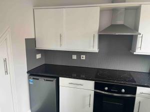 a kitchen with white cabinets and a black dishwasher at Nuneaton-GE Hospital 3 mins away in Nuneaton