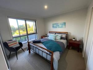 een slaapkamer met een bed, een stoel en een raam bij Self Contained Villa in Hawley Beach