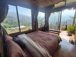 a bedroom with a bed in a room with large windows at Zoni Home Trạm Tấu in Cham Ta Lao