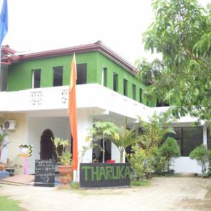 un edificio verde y blanco con un cartel delante en Tharuka Rest Inn Hotel en Tanamalwila