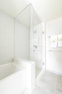 Brand New! Luxurious Sky Ala Moana 2 Bed 2 Bath في هونولولو: حمام ابيض مع دش وباب زجاجي