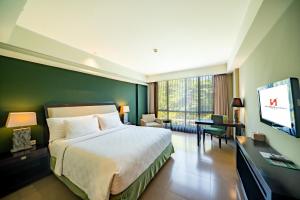 a hotel room with a bed and a flat screen tv at Swiss-Belhotel Rainforest in Kuta