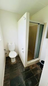 a bathroom with a toilet and a glass shower at Colosseum Creek Motel in Colosseum