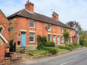 an old brick house with a blue door on a street at 1 Bed in Rutland Waters 60672 in Oakham