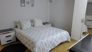 una camera da letto con un letto con un piumone bianco e uno specchio di Maison saba a Sevran