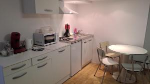 una cucina con forno a microonde, tavolo e sedie di Maison saba a Sevran