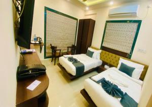 a hotel room with two beds and a desk and a television at One Infinity Residency in kolkata