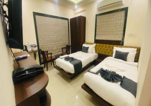 a hotel room with two beds and a television at One Infinity Residency in kolkata