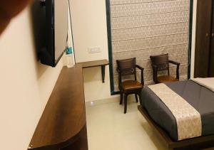 a bedroom with two chairs and a bed and a television at One Infinity Residency in kolkata