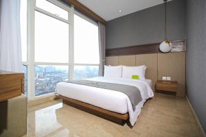 a bedroom with a large bed and a large window at Menteng Park Exclusive Emerald in Jakarta