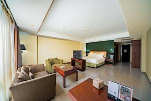 Habitación de hotel con cama y sala de estar. en Swiss-Belhotel Rainforest, en Kuta