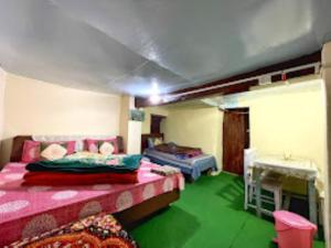 pokój z 2 łóżkami i zieloną podłogą w obiekcie YATRA HOMESTAY Joshimath w mieście Jyotirmath