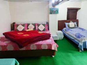 una camera con due letti con coperta rossa di YATRA HOMESTAY Joshimath a Joshīmath