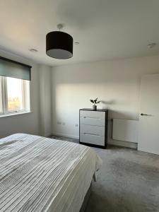 a white bedroom with a bed and a dresser at One bedroom Apartment in Barking