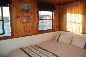 a bed in the back of a boat with windows at Knysna Houseboat Myrtle in Knysna