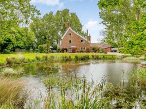 ein großes Backsteinhaus mit einem Teich davor in der Unterkunft 6 Bed in Norwich 42594 