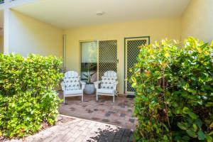 two white chairs sitting on a patio with bushes at Unit 10 Sails on Horseshoe in Horseshoe Bay