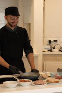 a man standing in a kitchen preparing food at Eva Mare Hotel & Suites - Adults only in Agia Pelagia +37 photos