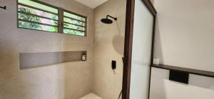 ein Bad mit einer Dusche und einem Fenster in der Unterkunft Villa Heirama in Punaauia