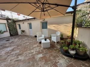 a patio with white chairs and an umbrella at Affittacamere Il Cortile in Chiaravalle