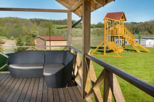 a porch with a swing and a playground at Sodyba ant ežero kranto pas Radvilą in Kiemeliai