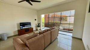 a living room with a couch and a flat screen tv at Villa Niu Center Canggu - FattyLion in Canggu