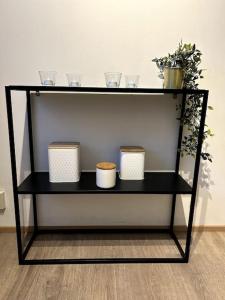 a black shelf with three cups and plants on it at Modern Apartment City Centre in Rovaniemi