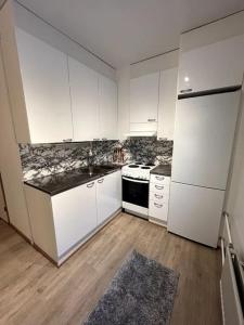 a kitchen with white cabinets and a white refrigerator at Modern Apartment City Centre in Rovaniemi